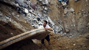 Palestinian salvages a mattress from the remains of a house, which police said was destroyed in an Israeli air strike, in Khan Younis in the southern Gaza Strip