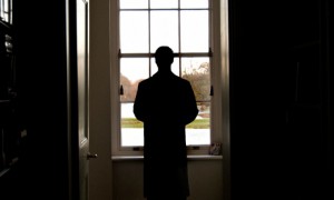 The silhouette of a man looking out of a window