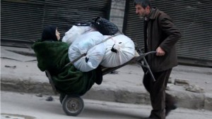 Seorang ibu tua dinaikkan ke atas gerobak bersama tumpukan barang di wilayah Aleppo, Suriah, 12 Desember 2016. 